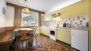 A compact kitchen with a dining area, a built-in oven, and a refrigerator. - Apartments Alara 134B (Ortisei)