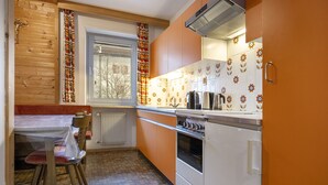 Een keuken met houten kastjes, een witte kookplaat en een raam met gordijnen.