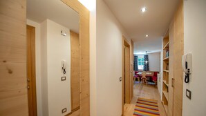 Un couloir aux murs et aux portes en bois, un tapis à rayures et, au fond, un coin repas.