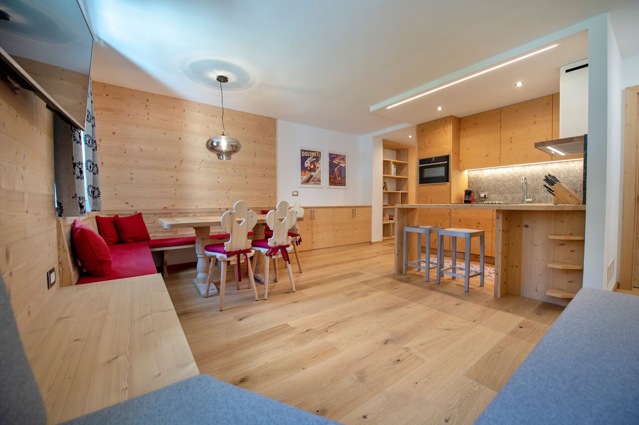 A modern kitchen with wooden cabinets, a dining area with a bench and chairs, and a small bar area.