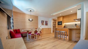 Une cuisine moderne avec des meubles en bois, un coin repas comprenant un banc et des chaises, et un petit espace bar.