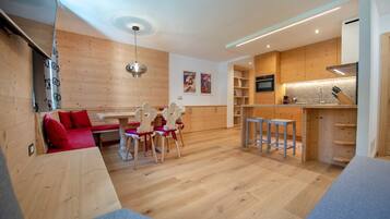 A modern kitchen with wooden cabinets, a dining area with a bench and chairs, and a small bar area.