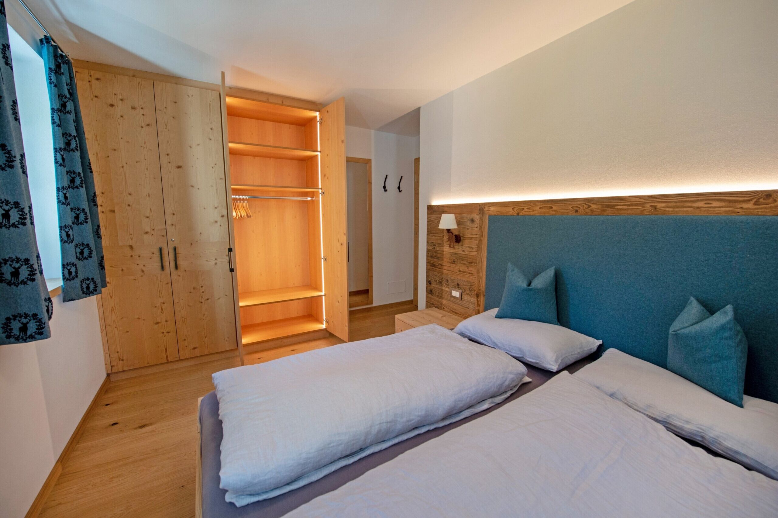 Camera da letto con due letti, un armadio in legno e una lampada da comodino.