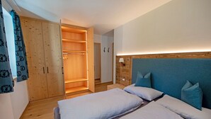 Une chambre avec deux lits, une armoire en bois et une lampe de chevet.