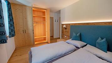 Camera da letto con due letti, un armadio in legno e una lampada da comodino.