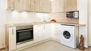 Eine moderne Küche mit Holzausstattung, Backofen, Mikrowelle und Waschmaschine.