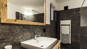 Une salle de bain moderne avec un grand miroir, un lavabo rectangulaire et un porte-serviettes.