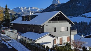 A modern house with a sloped roof, a balcony, and a view of snow-covered mountains. - Apartments Villa Mayr 125A (Ortisei)