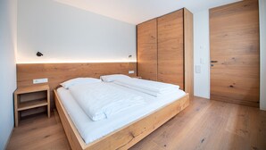 A modern bedroom with a wooden bed frame, a nightstand, and a wardrobe. - Apartments Villa Mayr 125A (Ortisei)