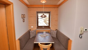 A compact room with a wooden table and bench seating, a window with a view, and a telephone on the wall. - Apartments Nogler Frieda 124A (Selva di Val Gardena)