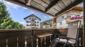 Un balcon avec une table et une chaise en bois, donnant sur une ville aux bâtiments traditionnels.