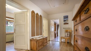 Un couloir avec un plancher en bois, un banc en bois, une chaise et une commode à tiroirs.
