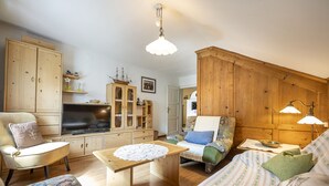Un salon chaleureux, avec des meubles en bois, un téléviseur et un buffet en bois.