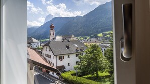 Une vue d’une ville avec un clocher d’église imposant, entourée de bâtiments et de montagnes.
