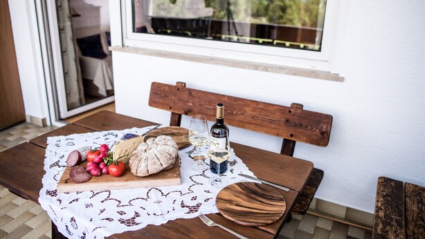A wooden table with a lace tablecloth, a wooden bench, and a window with a view of mountains. - Apartments Matilde 201A (Fiè allo Sciliar)