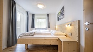Une chambre moderne avec un lit en bois, une table de chevet et une fenêtre avec des rideaux.