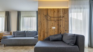 Un salon moderne avec deux canapés gris, un mur d’accent en bois et un sol carrelé.