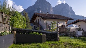 Une maison avec un toit en pente, un mur en pierre et une clôture en bois.