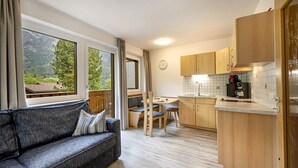 Une cuisine moderne avec des meubles en bois, un coin repas avec un banc et un canapé offrant une vue sur l’extérieur.