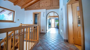 A hallway with wooden flooring, a wooden railing, and a tiled ceiling.
