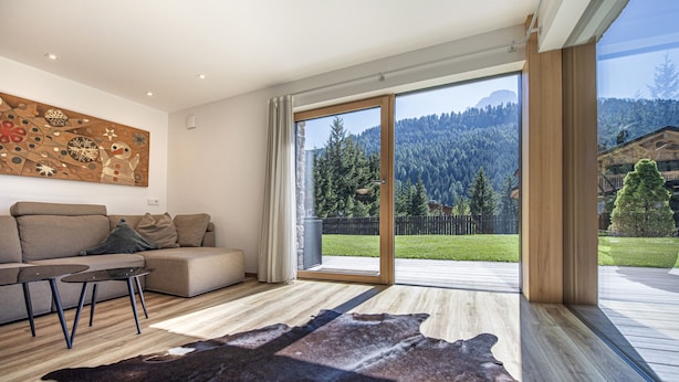 Ein modernes Wohnzimmer mit einer Couch, einem Couchtisch und einem großen Fenster mit Blick auf einen bewaldeten Berg.
