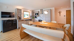 Eine moderne Küche mit einem Holzespeisetisch und einer Bank, eingebauten Geräten und einem Kruzifix an der Wand.