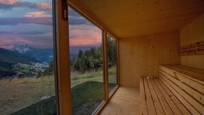 Un interno in legno con un'ampia vetrata che si affaccia su un paesaggio montuoso.