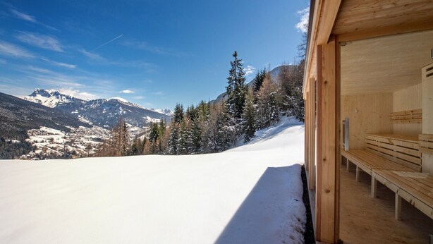 A wooden cabin with a bench inside, overlooking a snowy mountain landscape. - Residence Chalet Alpina 143E (Ortisei)