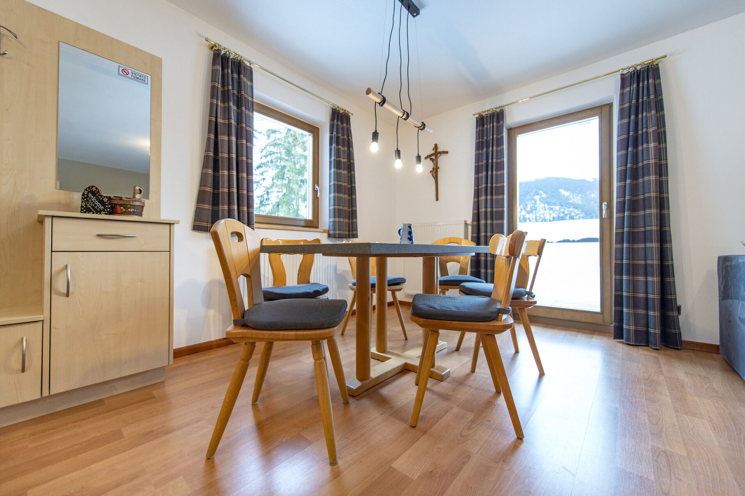 Ein Essbereich mit Holztisch und Stühlen, einem Spiegel und Blick ins Freie.