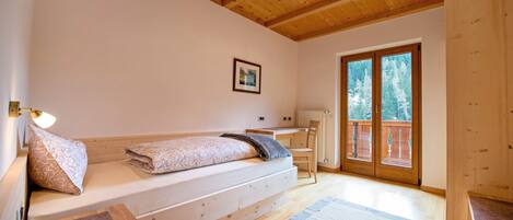 Un dormitorio con techo de madera, una cama con cabecera, un escritorio y una silla.