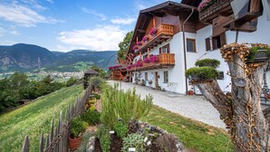 Ein traditionelles Chalet mit Holzbalkonen, einem Kiesweg und Blick auf ein Tal.