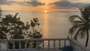 A balcony with a view of the sea during sunset.