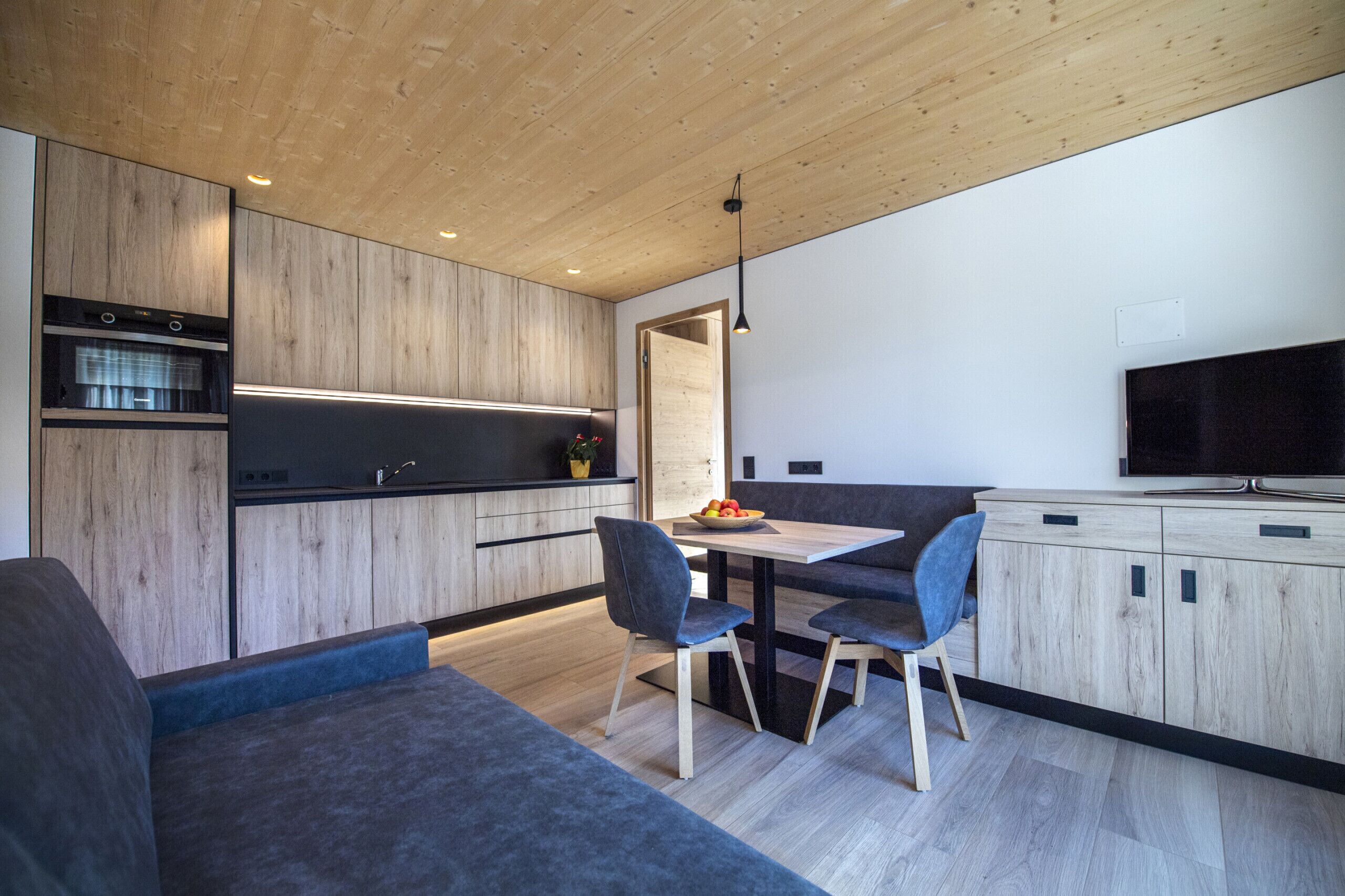 Eine moderne Küche mit Holzschränken, einem Esstisch und Stühlen.