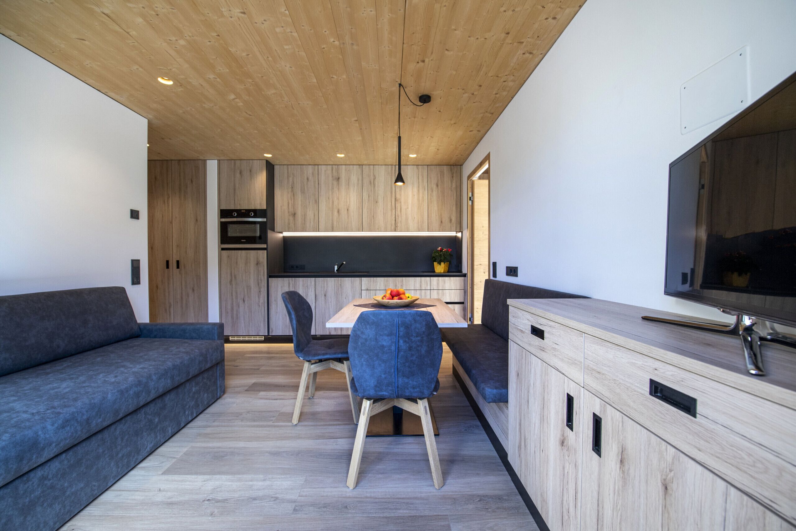 Una cocina moderna con armarios de madera, una mesa de comedor y un horno empotrado.