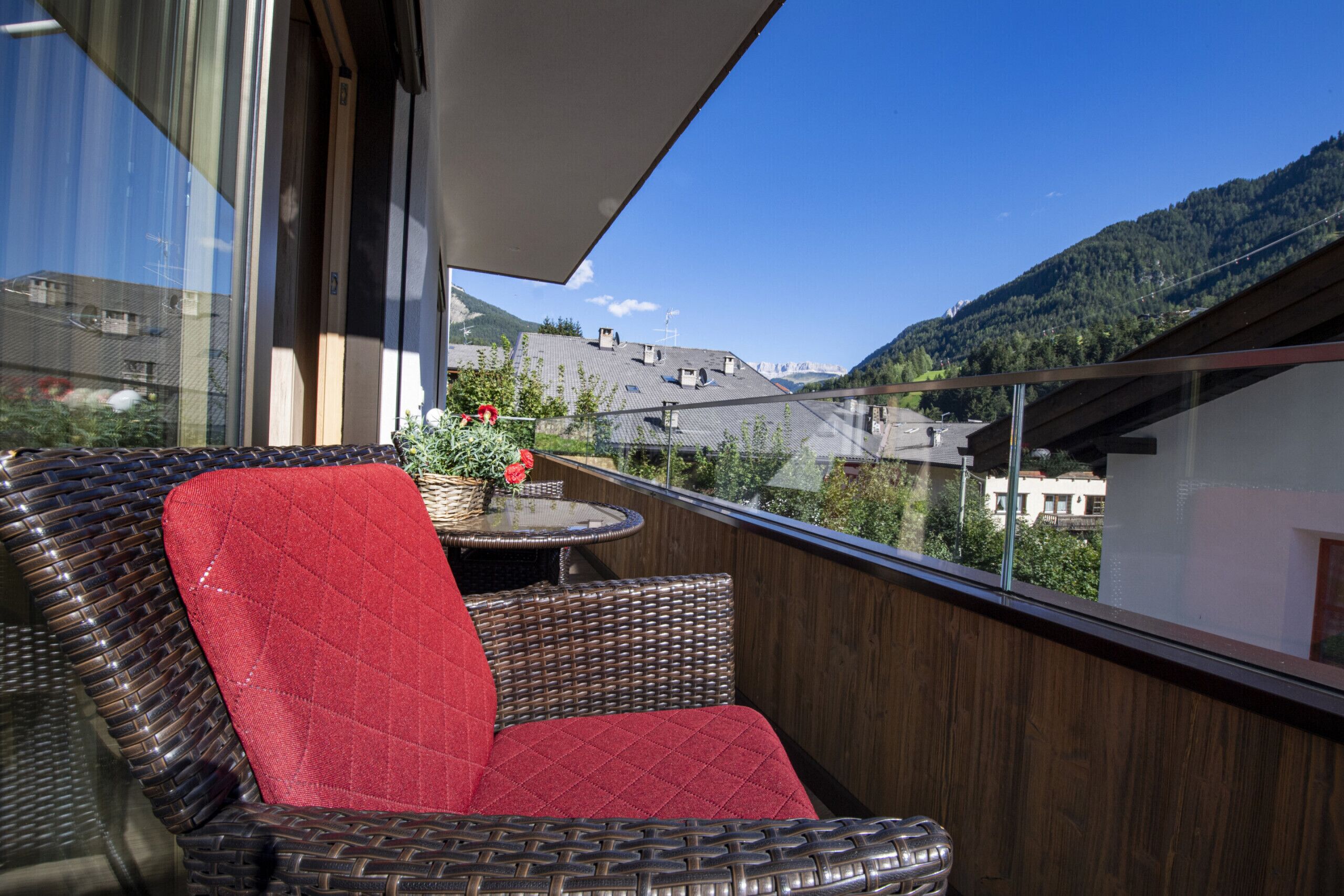 Un balcon doté de meubles en osier et offrant une vue sur un paysage montagneux.