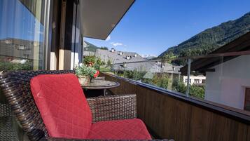 Un balcon doté de meubles en osier et offrant une vue sur un paysage montagneux.
