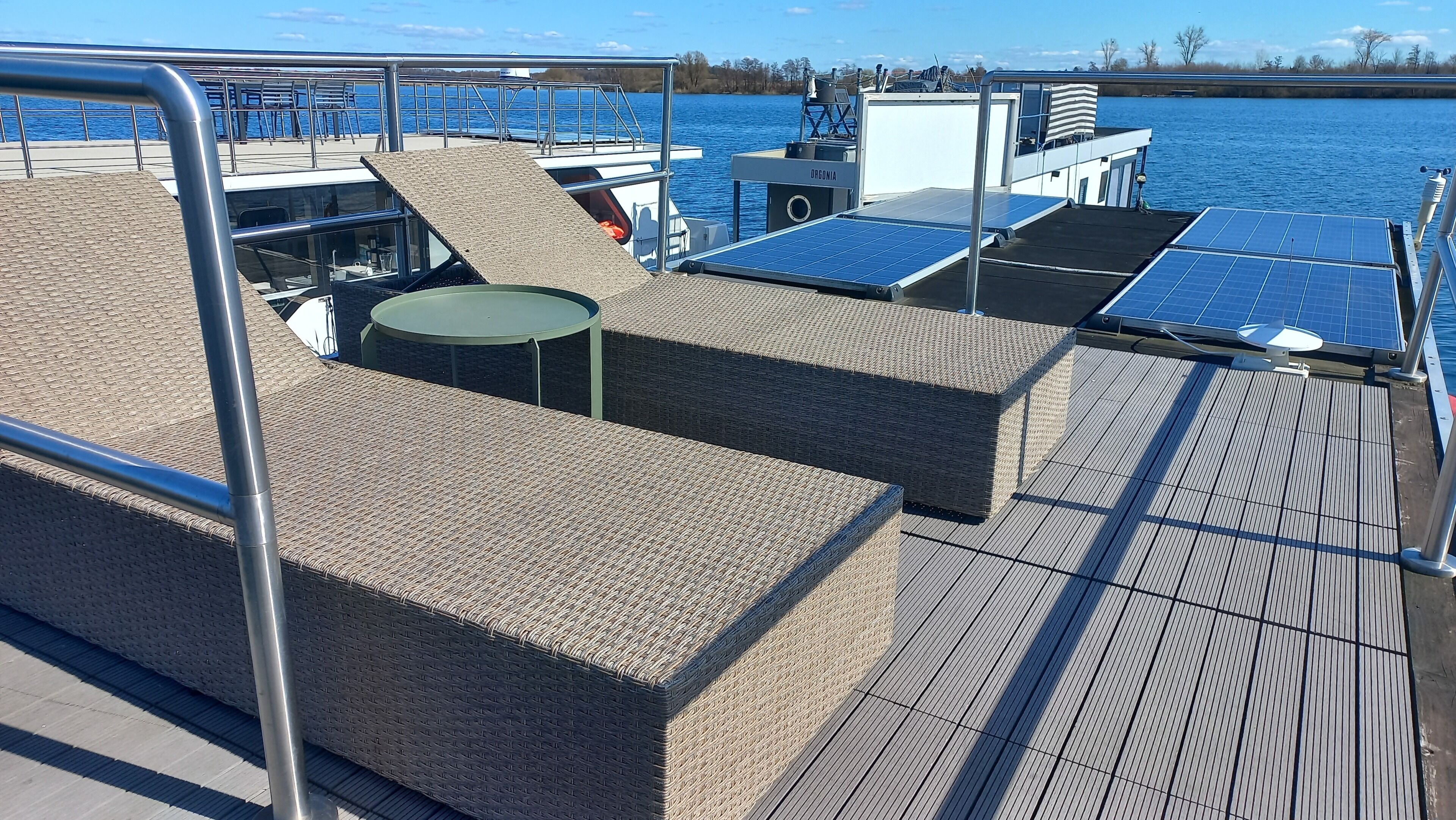 A deck with wicker furniture, solar panels, and a railing.