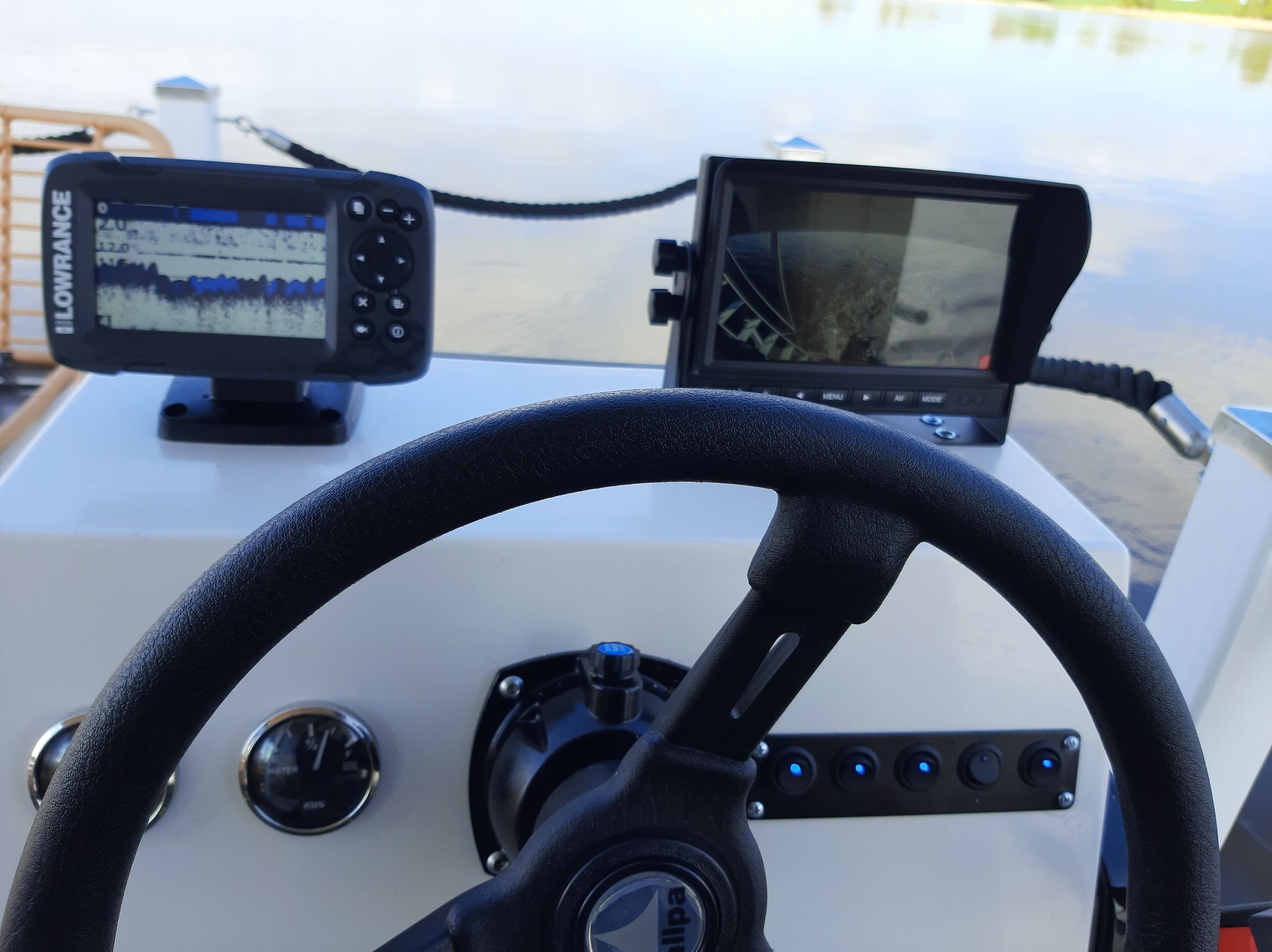 A boat's control panel with a steering wheel, a navigation display, and a speedometer.