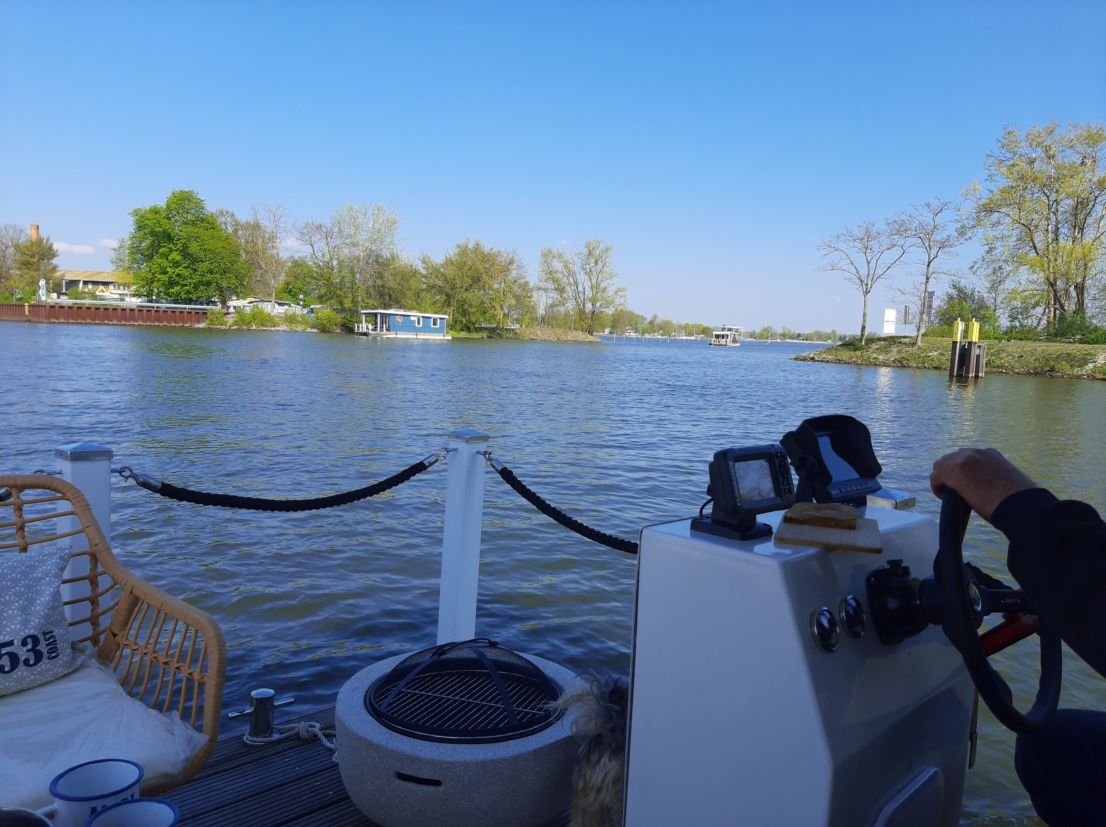 Ein Boot mit Steuerrad, Kamera und Korbsessel mit Kissen.