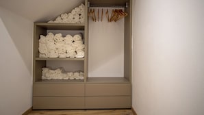 A minimalist wardrobe with multiple shelves for folded clothes and a hanging rod for garments.