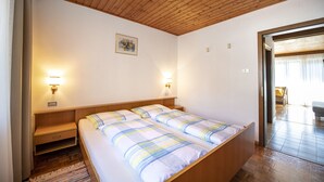 Een slaapkamer met een houten plafond, twee nachtkastjes met lampen, een bed met gestreept beddengoed en een klein schilderij aan de muur.