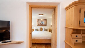 Un dormitorio con una cama de madera, un televisor en un estante y un cuadro en la pared.