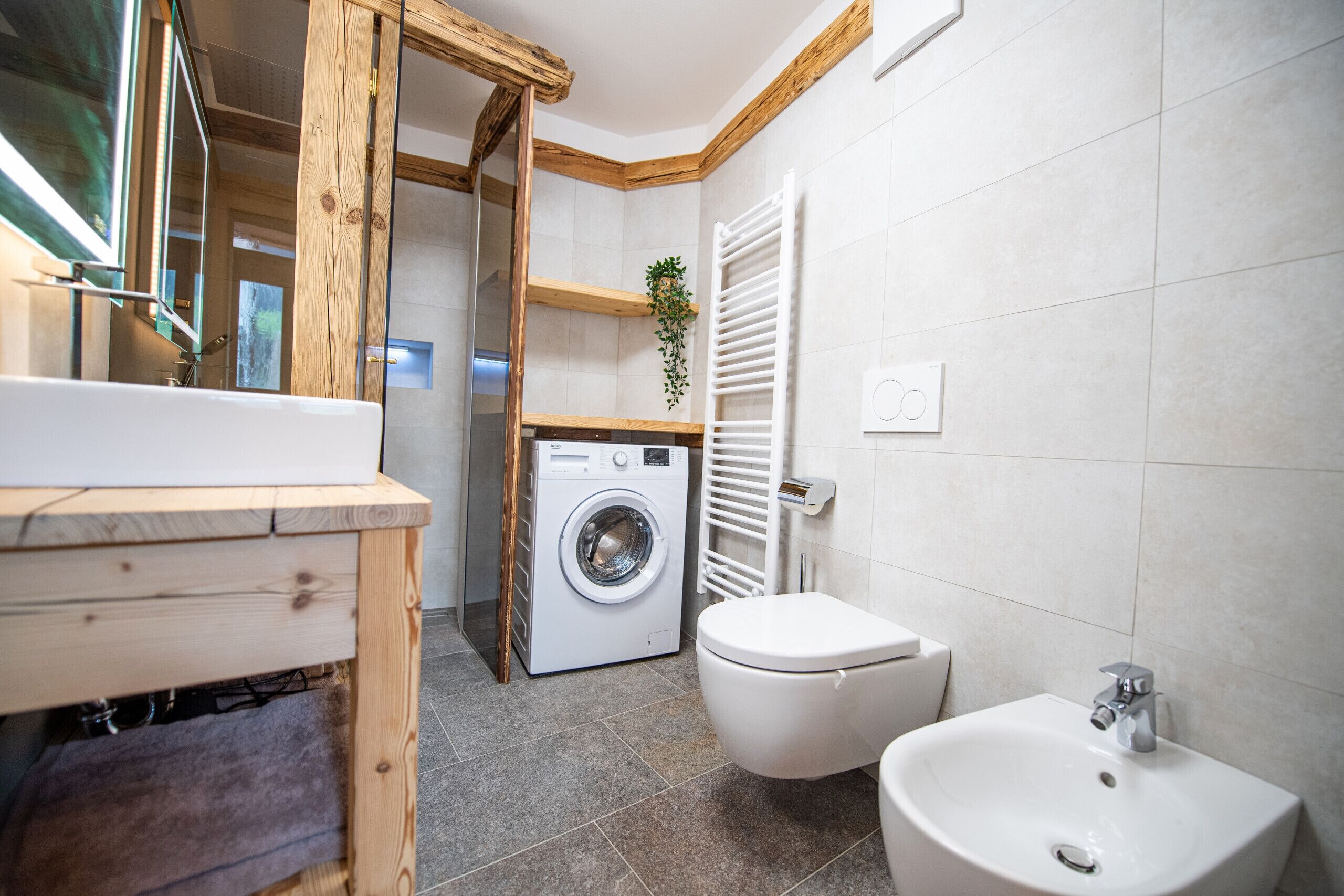 Une salle de bain moderne équipée d’un lave-linge, de toilettes et d’un lavabo.