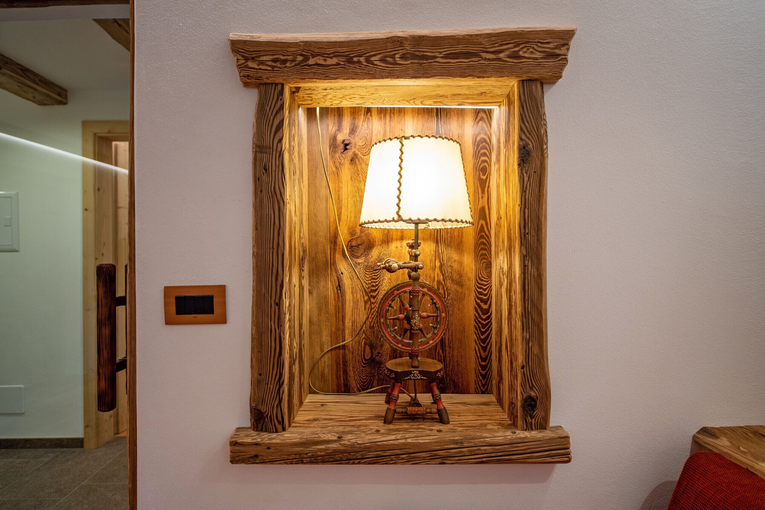Una lampada da parete in legno con paralume bianco e base decorativa.