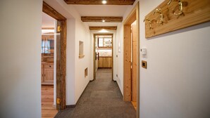 Un pasillo con vigas de madera, suelo de baldosas y un perchero de madera.
