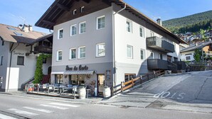 Ein zweistöckiges Gebäude, im Erdgeschoss befindet sich das Restaurant "Casa da Carla". Es gibt Tische und Stühle im Freien, einen Holzzaun und eine Straße davor.