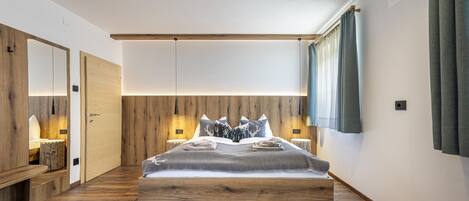 Une chambre avec un lit en bois, une table de chevet, un miroir et un plancher en bois.