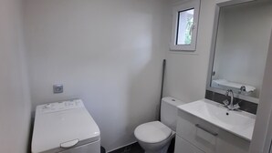 A compact bathroom with a white toilet, a sink with a mirror, and a washing machine. - Country cottage (Flassans-sur-Issole)