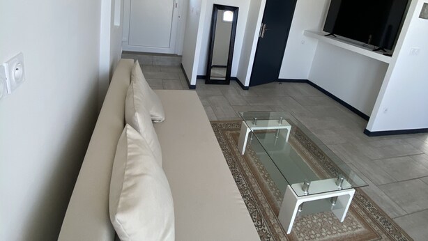 Un salon moderne avec un canapé beige, une table basse en verre et un tapis à motifs.