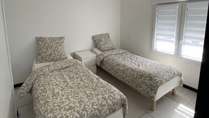 Une chambre avec deux lits, une table de chevet et une fenêtre avec des stores.
